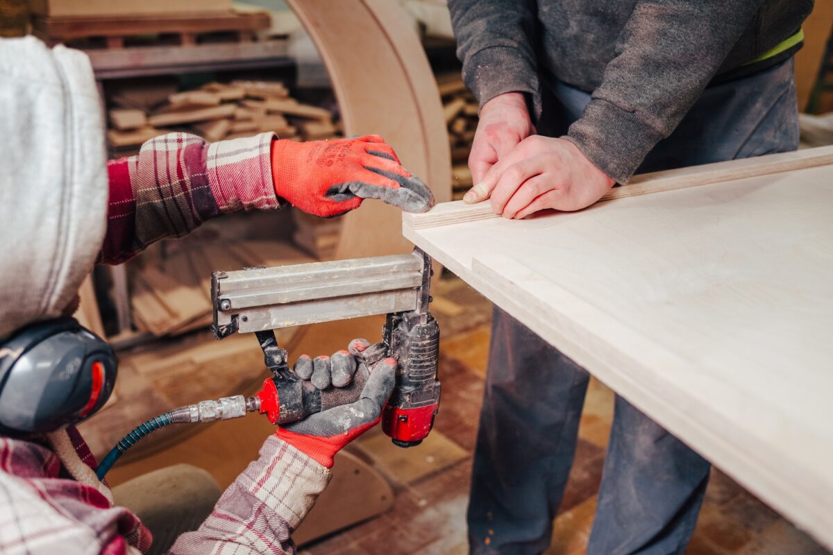 Carpenter hammering nails into plywood with a pneumatic nailer
